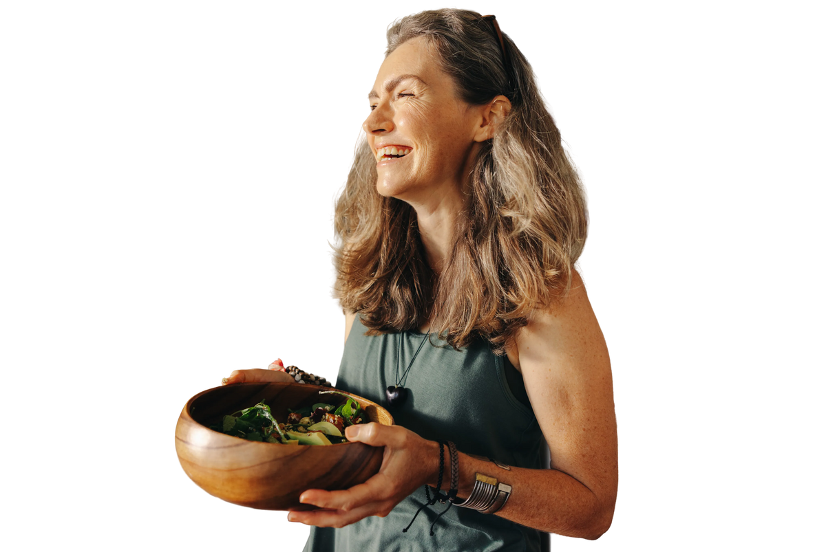 Woman smiling while holding a bowl of fresh salad.